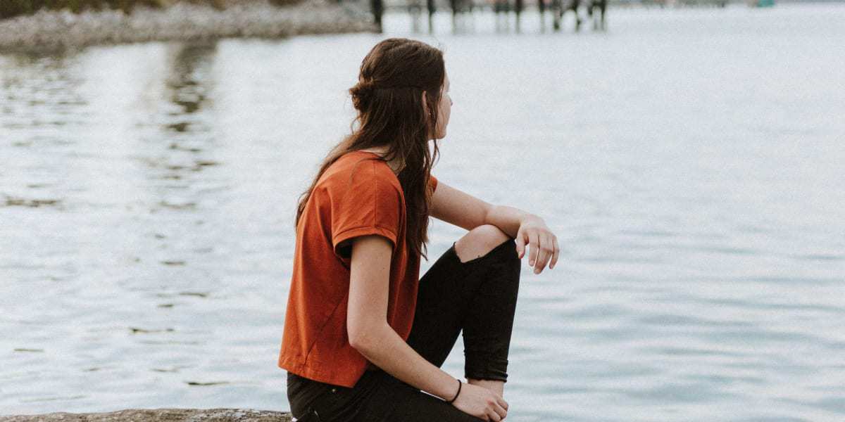 woman sitting on dock thinking about getting through divorce unscathed