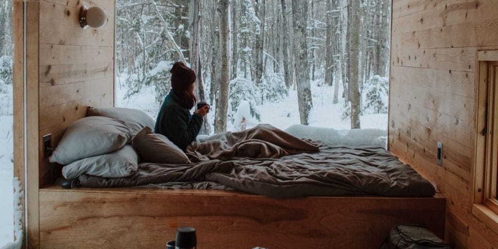 Tiny House Divorce Rate: What Every Tiny Home Buyer Needs to Know 2 woman in bed watching it snow, considering the tiny house divorce rate