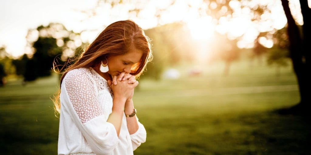Woman praying a Prayer for Domestic Violence in a field