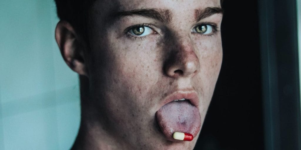 young man with pill on tongue with thoughts about the best defense strategy for a drug possession charge